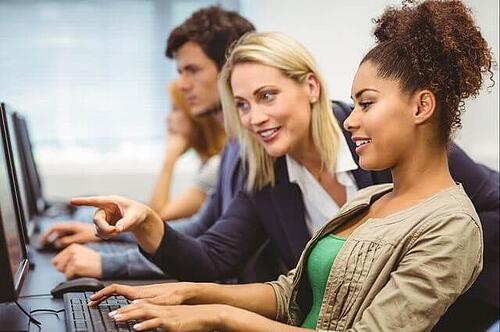 Marketing professor pointing to a student's computer screen during a lesson on alt text